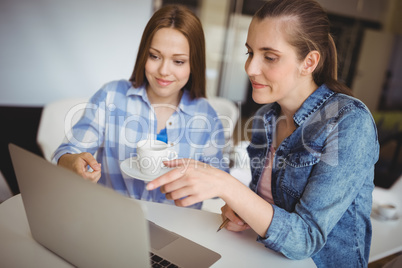 Businesswomen working on laptop at desk in creative office