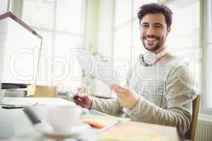 Smiling businessman holding papers in creative office