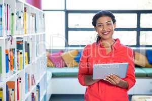 Porrait of teacher using digital tablet in school library