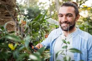 Portrait of confident gardener using hedge clippers at garden