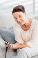 Portrait of smiling mature woman holding smartphone