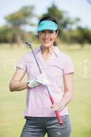 Portrait of confident woman carrying golf club