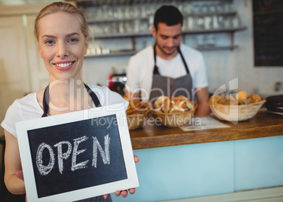 Portrait of confident waitress holding chalkboard