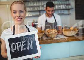 Portrait of confident waitress holding chalkboard