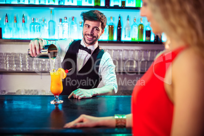 Bartender looking at woman while pouring cocktail in glass