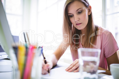 Graphic designer writing document at desk