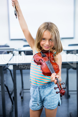 Happy girl playing violin in classroom