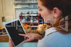 Barista scrolling digital tablet at cafe