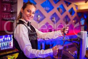 Portrait of happy barmaid pouring beer in glass