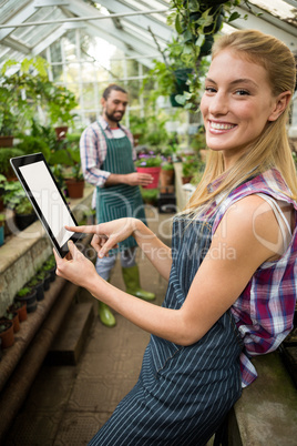 Portrait of happy gardener using digital tablet at greenhouse