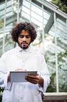 Male scientist using tablet computer outside greenhouse
