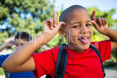 Playful schoolboy making a face at school campus