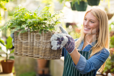 Woman holding plant in wicker basket at greenhouse