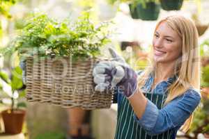 Woman holding plant in wicker basket at greenhouse