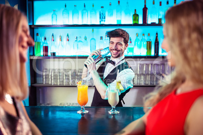 Barkeeper preparing cocktail for female customers