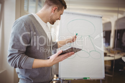 Businessman holding digital tablet while giving presentation in