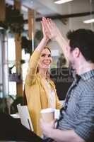 Creative businesswoman giving high-five to male coworker