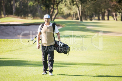Sportsman walking with his golf bag