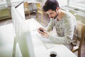 Young businessman using mobile phone at desk in office