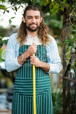 Portrait of happy gardener holding work tool at garden
