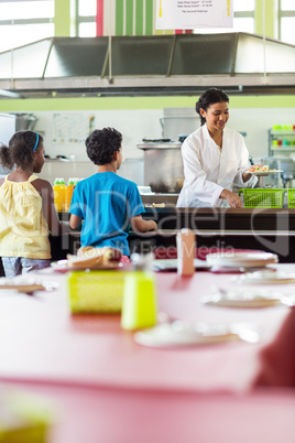 Woman serving food to schoolchildren