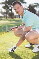Portrait of confident golfer man placing golf ball on tee