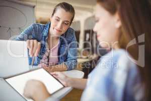 Businesswoman pointing on digital tablet with colleague in offic