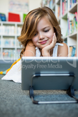 Smiling girl using digital tablet in school library