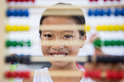 Smiling girl in front of abacus in classroom