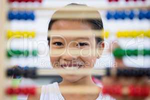 Smiling girl in front of abacus in classroom