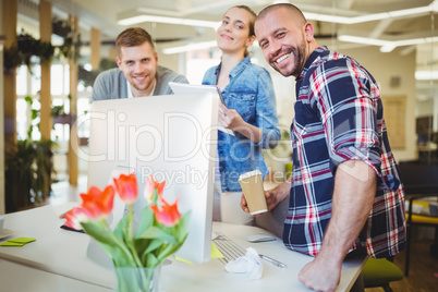 Smiling business people standing at desk in creative office