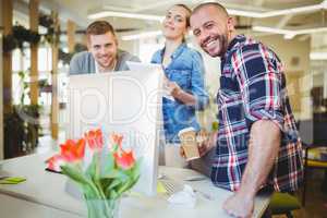 Smiling business people standing at desk in creative office