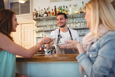 Happy waiter serving coffee to customer at cafeteria