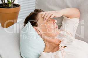 Close-up of mature woman having headache while lying on sofa