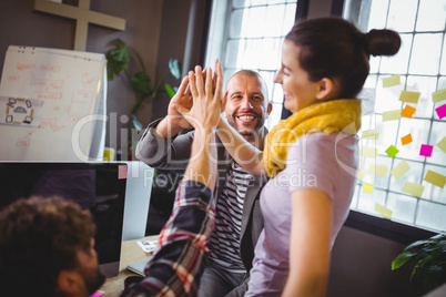 Coworkers high fiving in creative office