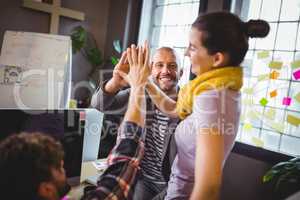 Coworkers high fiving in creative office