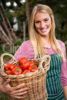 Portrait of happy gardener carrying tomatoes basket at garden