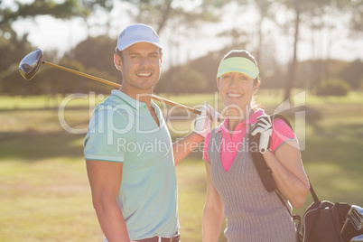 Portrait of smiling couple with bag and golf club