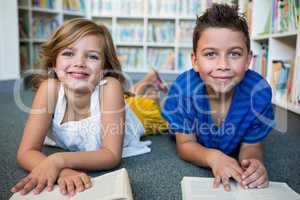 Portrait of girl and boy lying at library in school