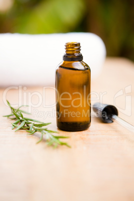 Aromatherapy oil bottle by rosemary on table