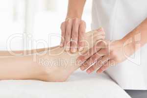 Midsection of masseur giving foot massage to woman