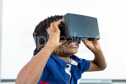 Smiling boy using virtual reality headset in classroom