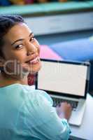 portrait of woman using laptop in library