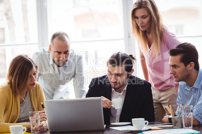 Business people using laptop during meeting