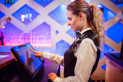 Barmaid using modern cash register at bar counter