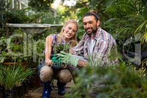 Portrait of happy colleagues holding potted plants at garden