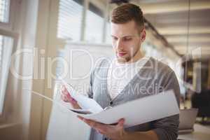 Young businessman holding file at creative office