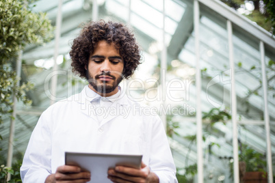 Male scientist using digital tablet outside greenhouse