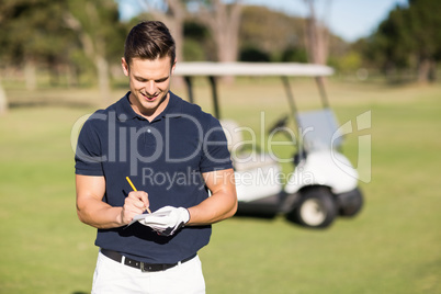 Smiling golfer writing on score card