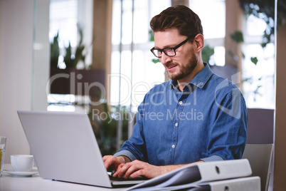 Confident businessman working on laptop at creative office